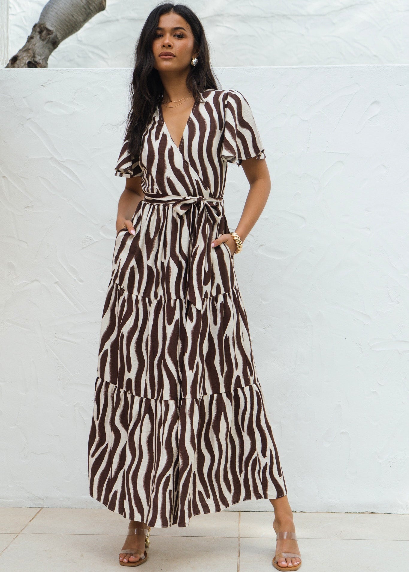 Woman wearing a zebra print dress against a white brick wall.