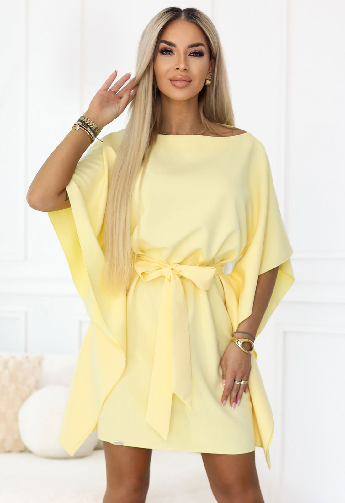 Woman wearing a yellow dress with a belt in a minimalistic setting