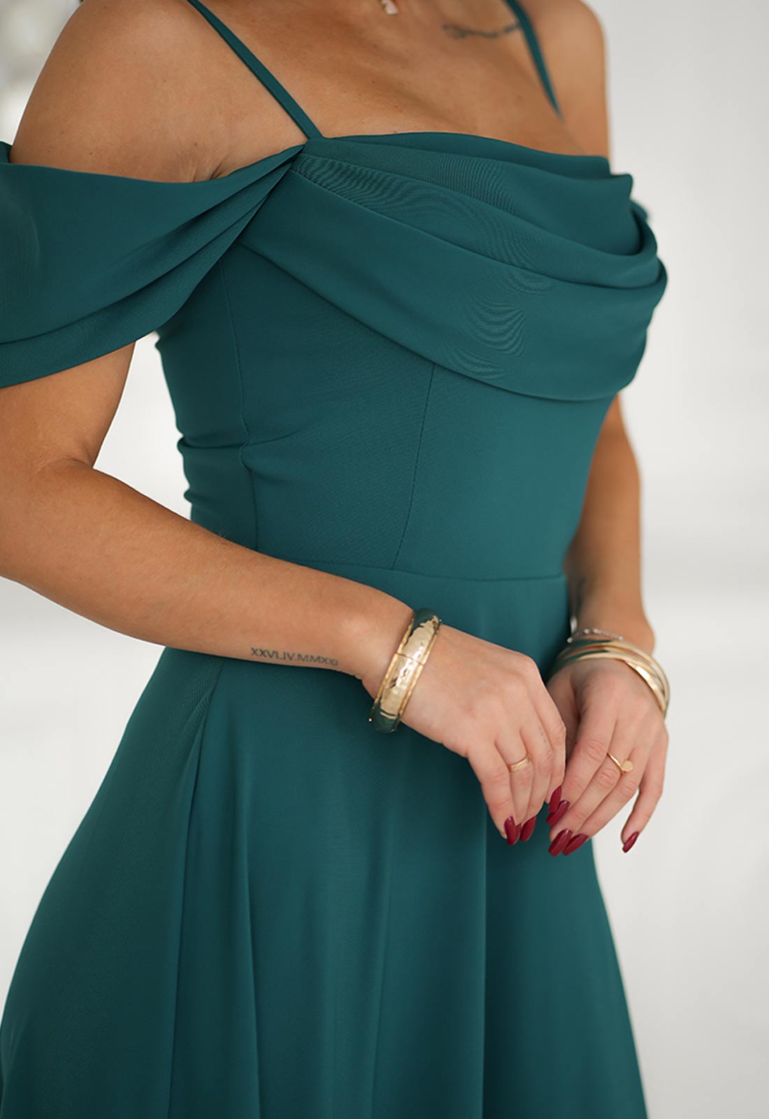 Teal dress with thin straps and a draped bodice on a white background