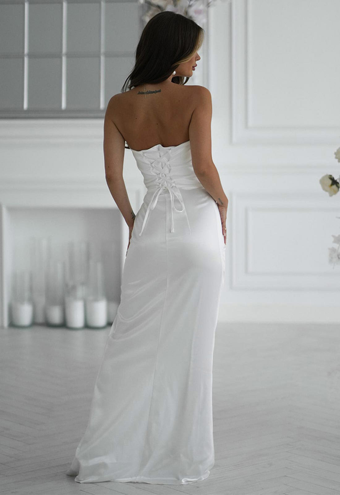 Woman wearing a white strapless gown in a room with white walls and decor.
