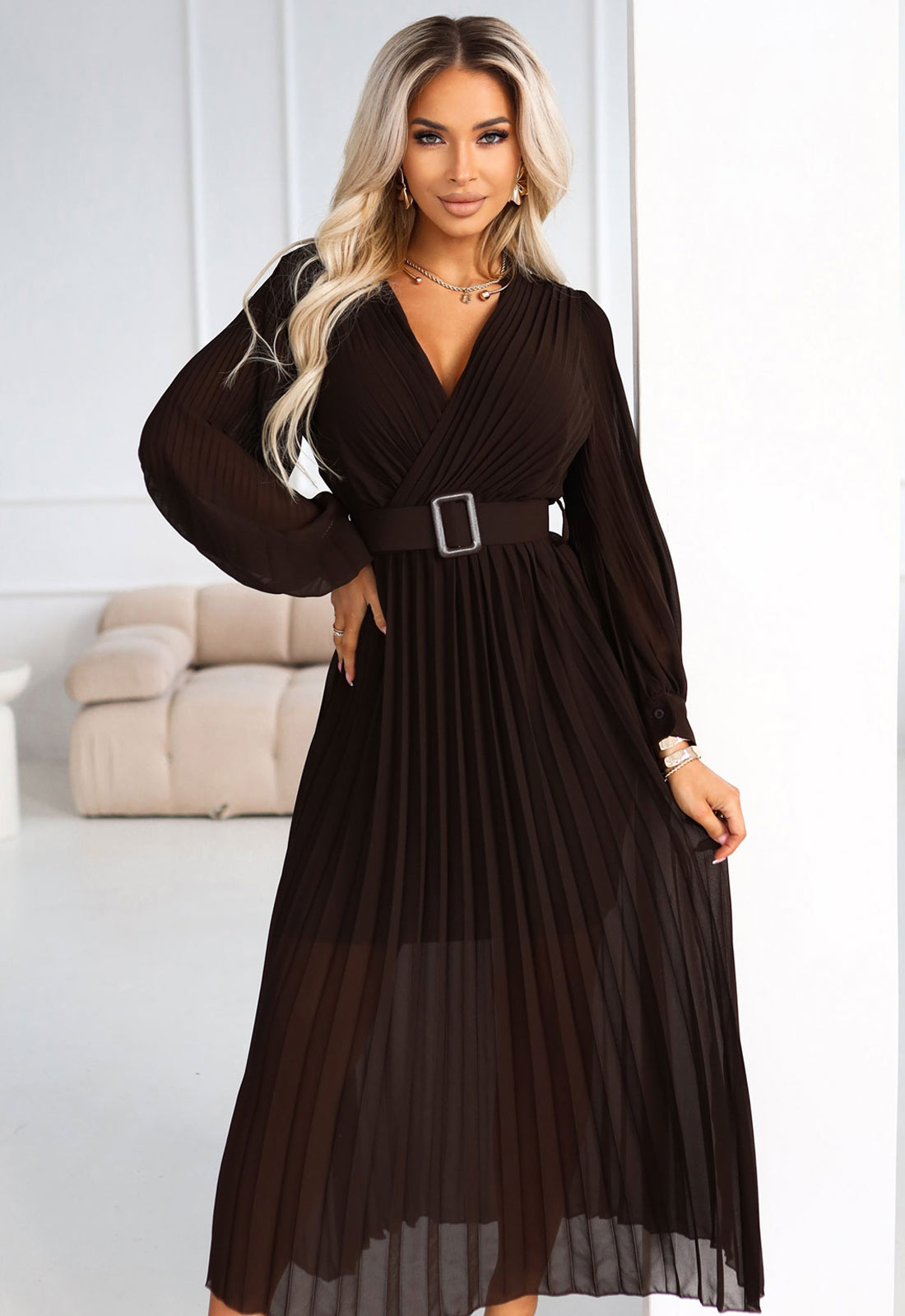 Woman wearing a brown dress with a belt in a room.