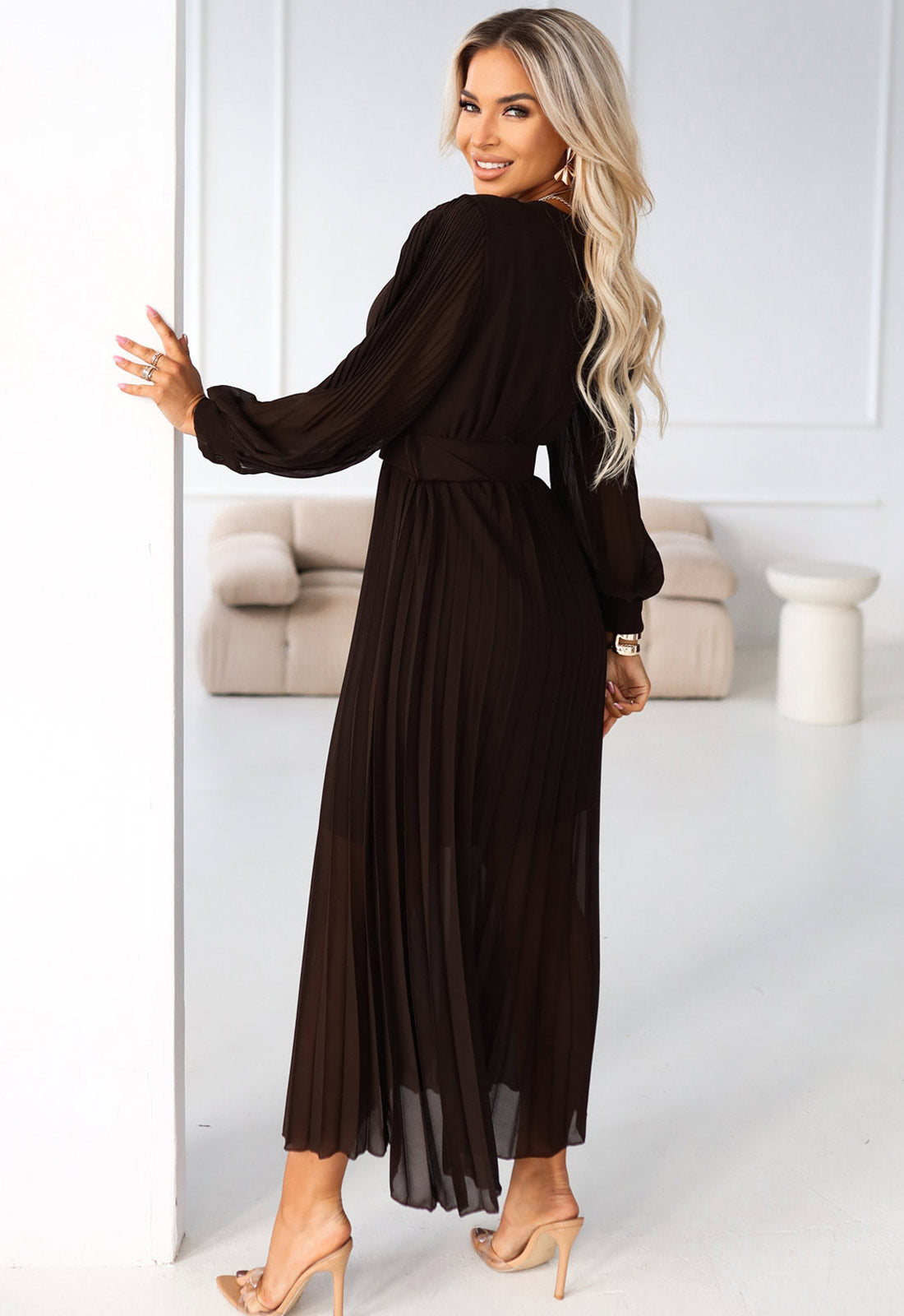 Woman wearing a black dress in a minimalistic room.