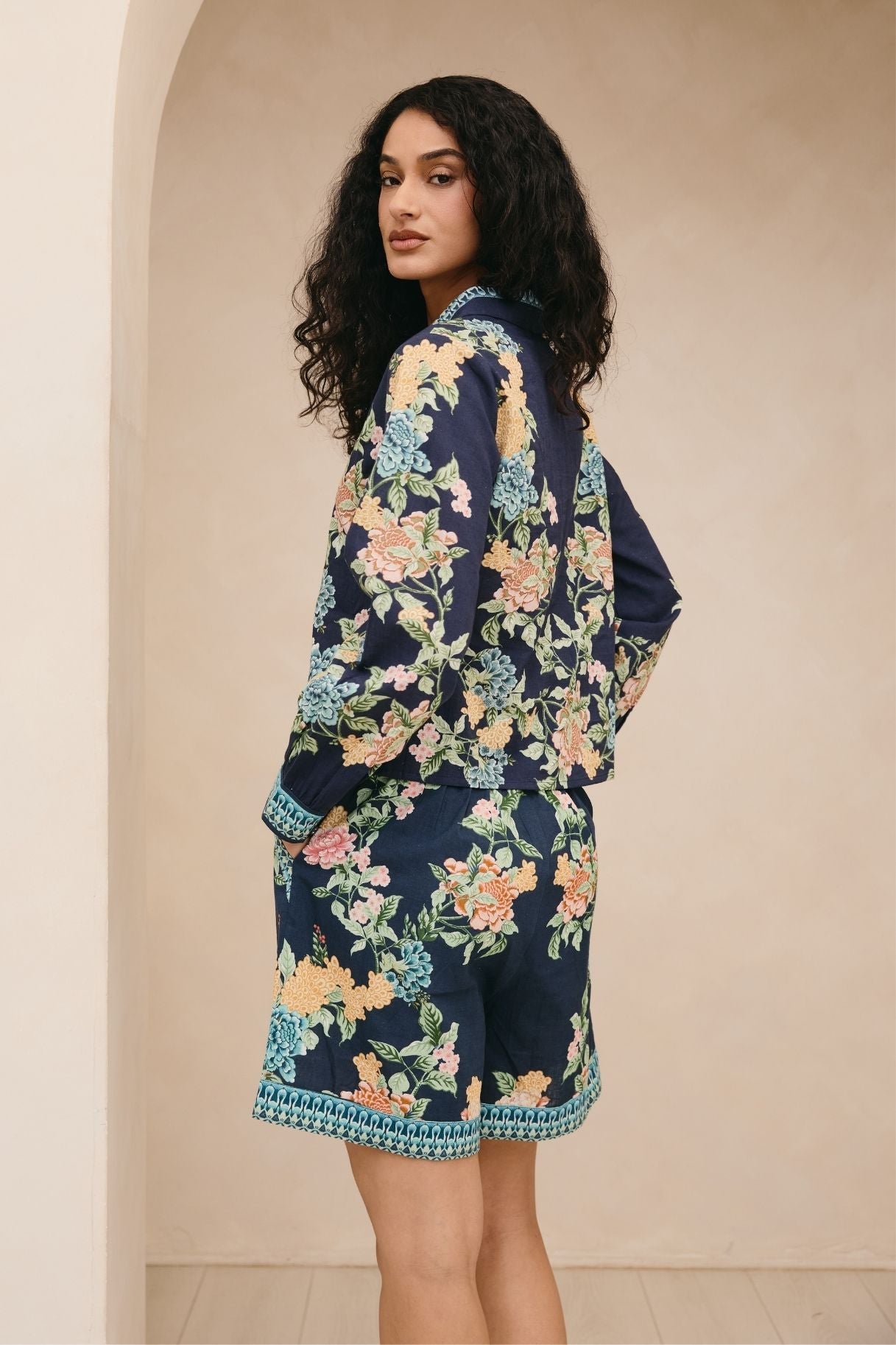 Woman wearing a navy floral kimono against a beige wall.