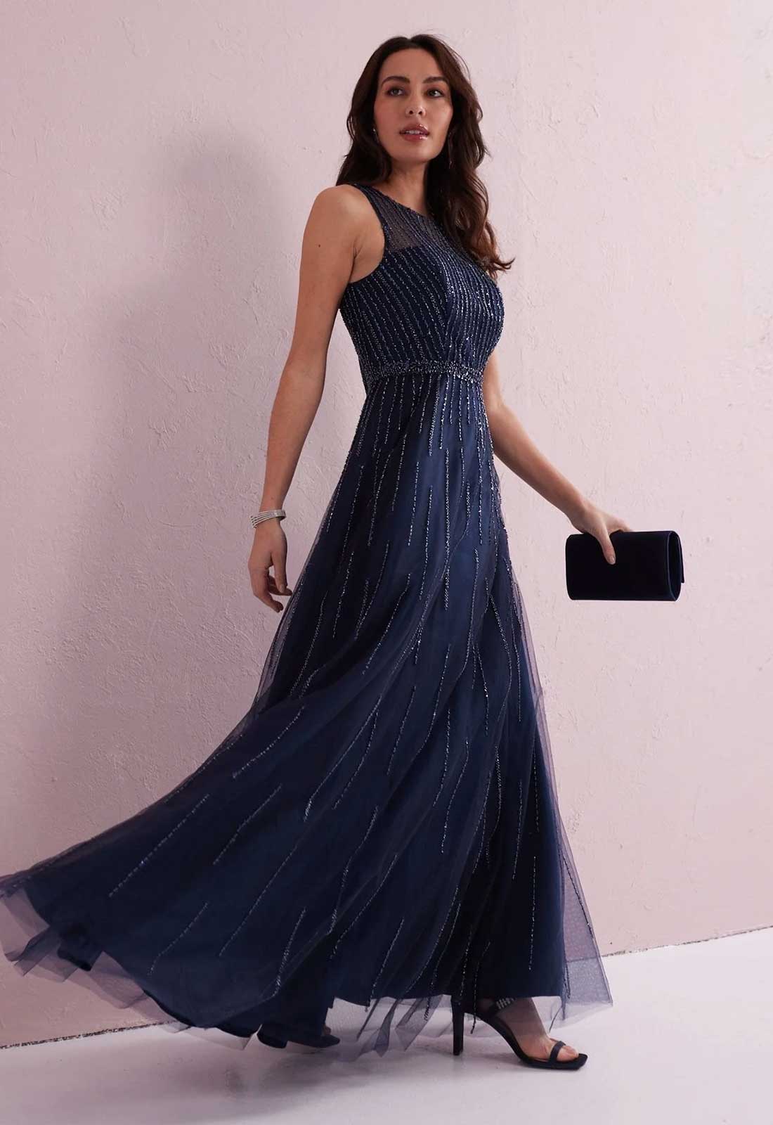 Woman wearing a navy blue evening gown with a white background