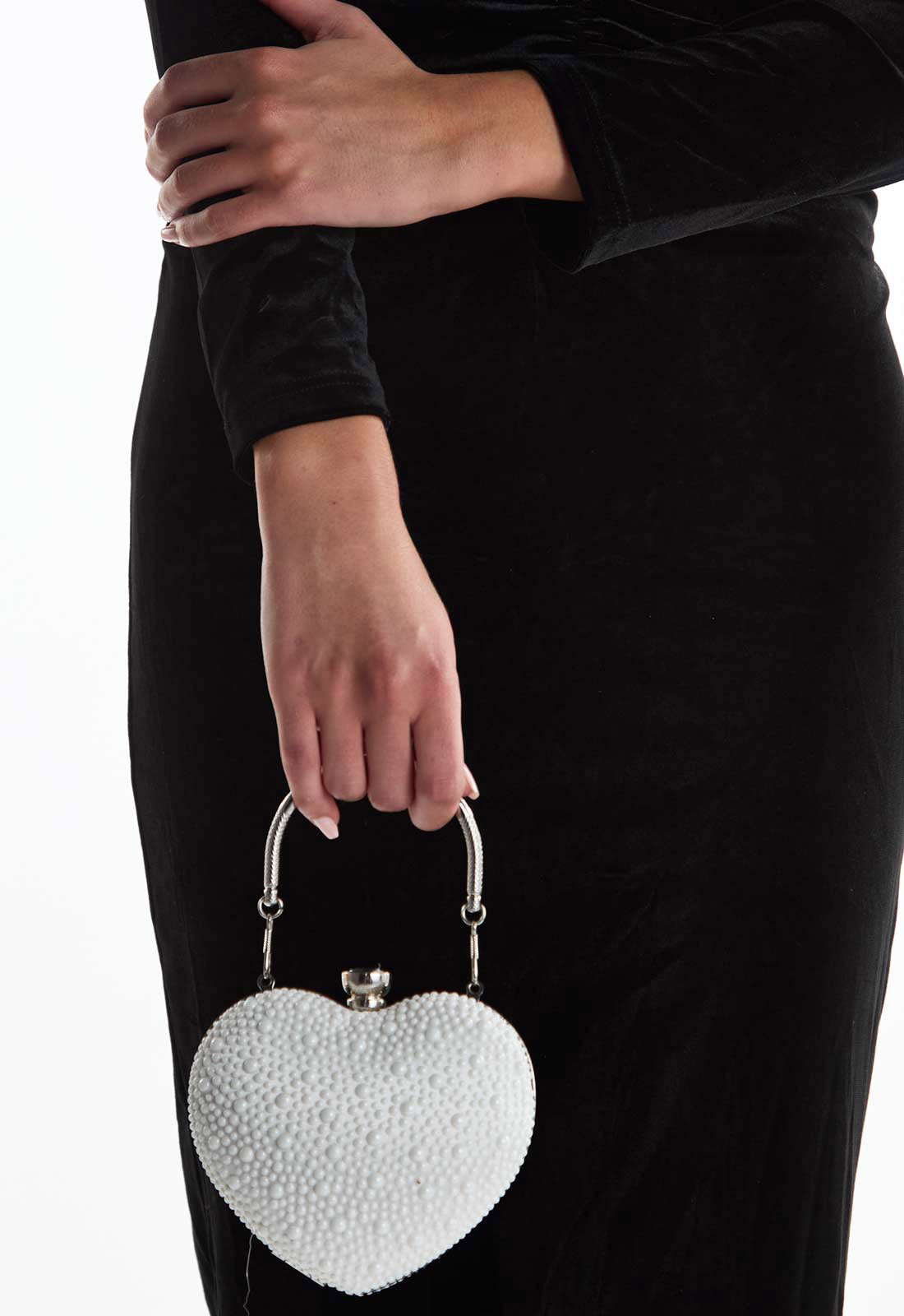 Heart-shaped beaded handbag held by a person wearing a black outfit.