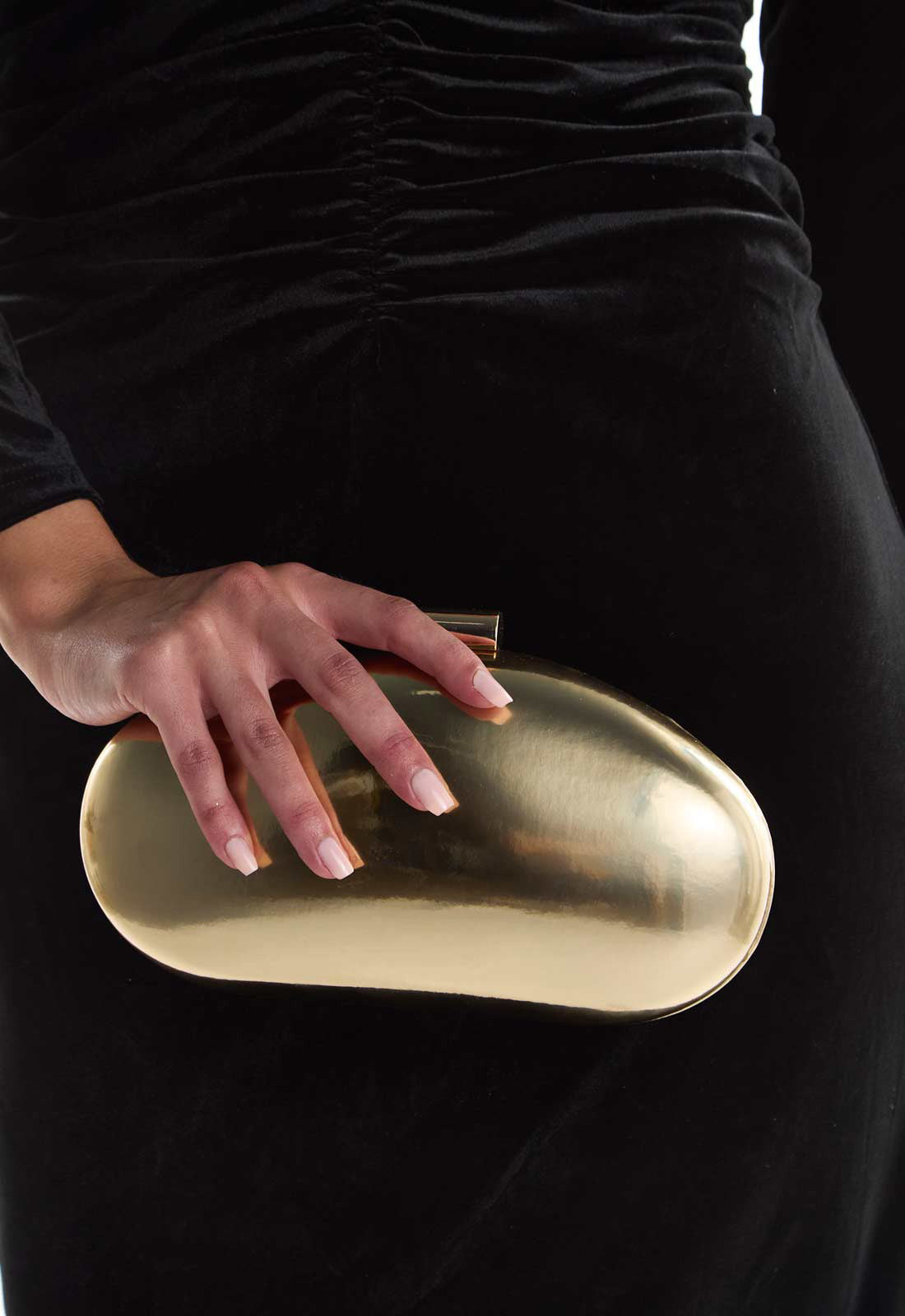 Person holding a gold clutch against a black background