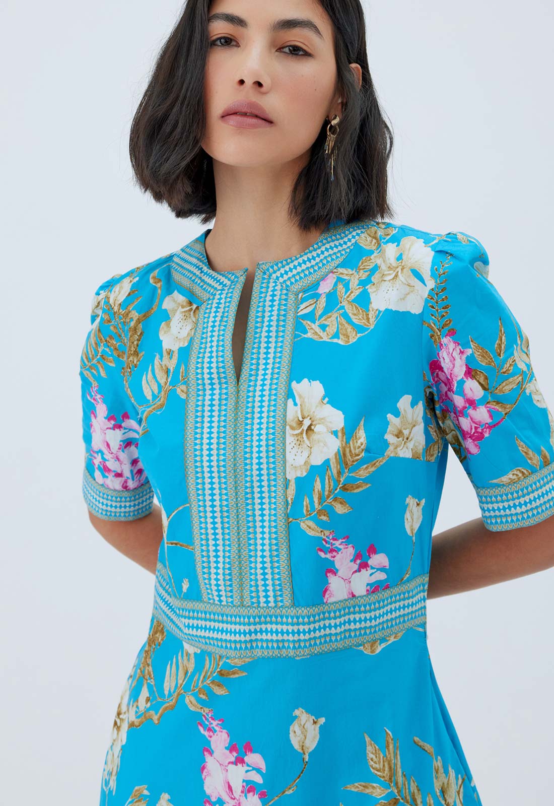 Woman wearing a blue embroidered dress with floral patterns on a white background