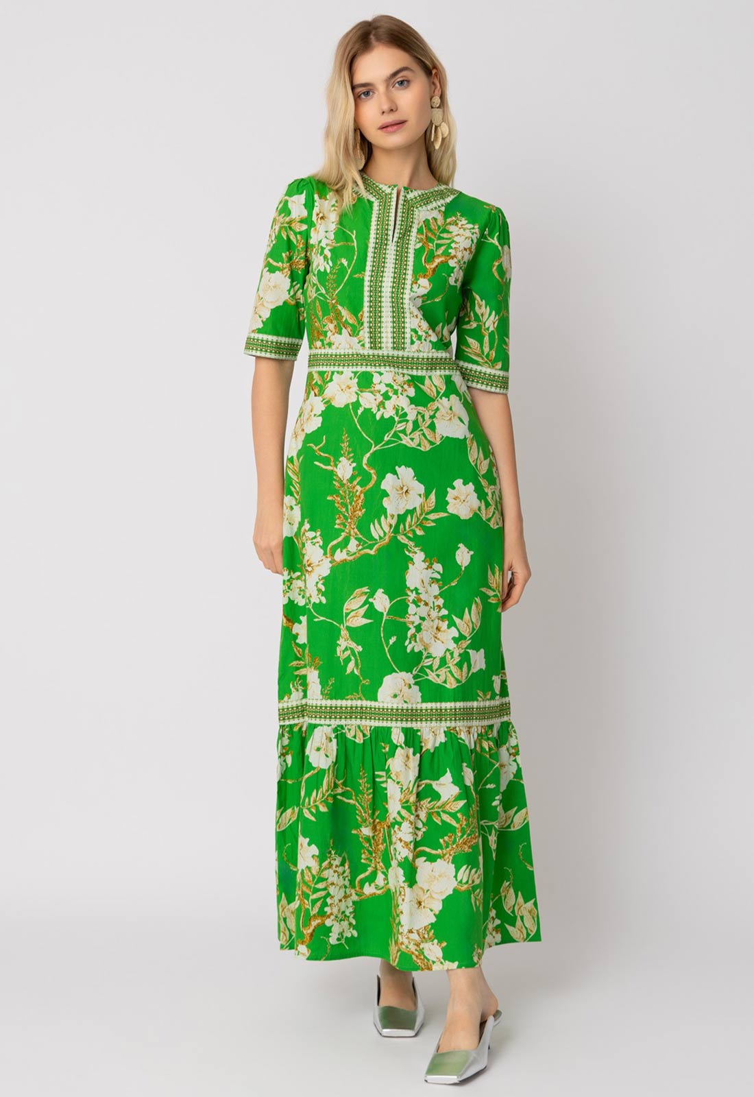 Woman wearing a green floral dress against a white background