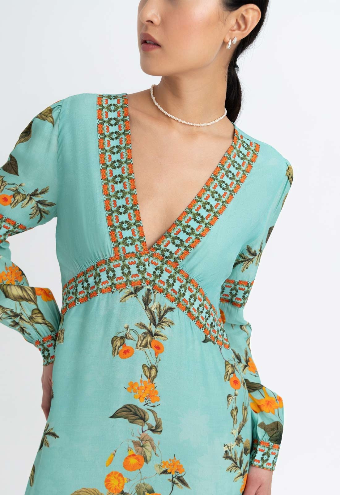 Light blue dress with floral patterns and a deep neckline on a white background