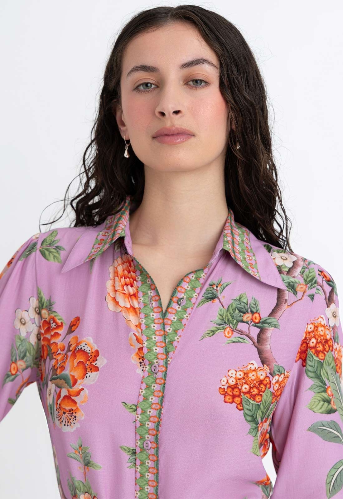 Woman wearing a purple floral blouse against a white background