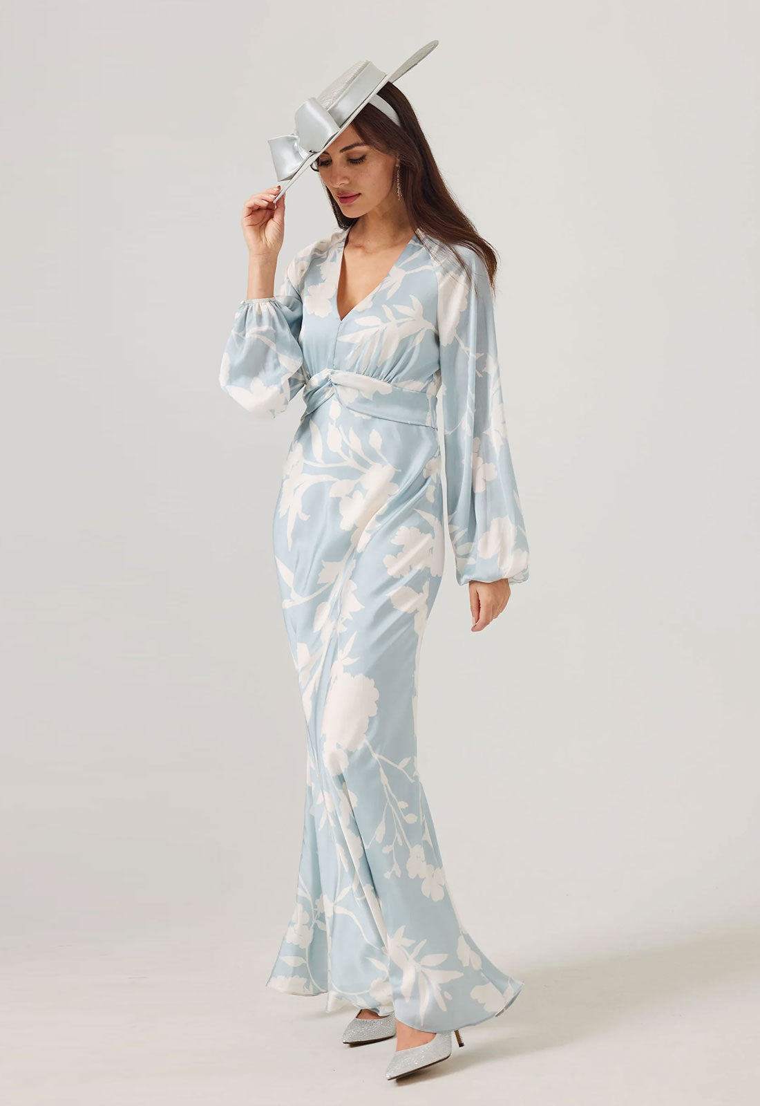 Woman wearing a light blue and white patterned dress with a hat on a white background