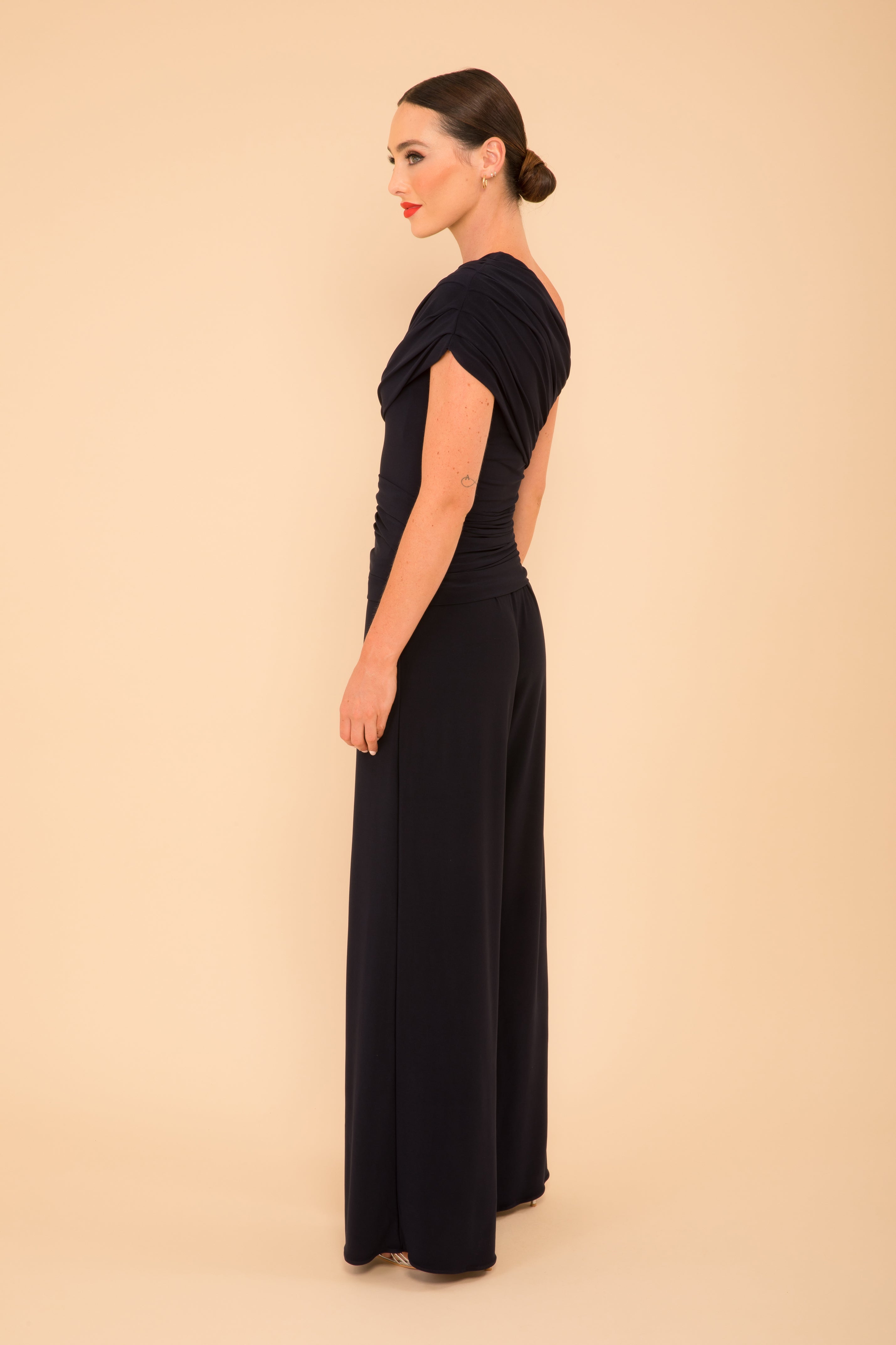 Woman wearing a black dress with cut-out sides on a beige background
