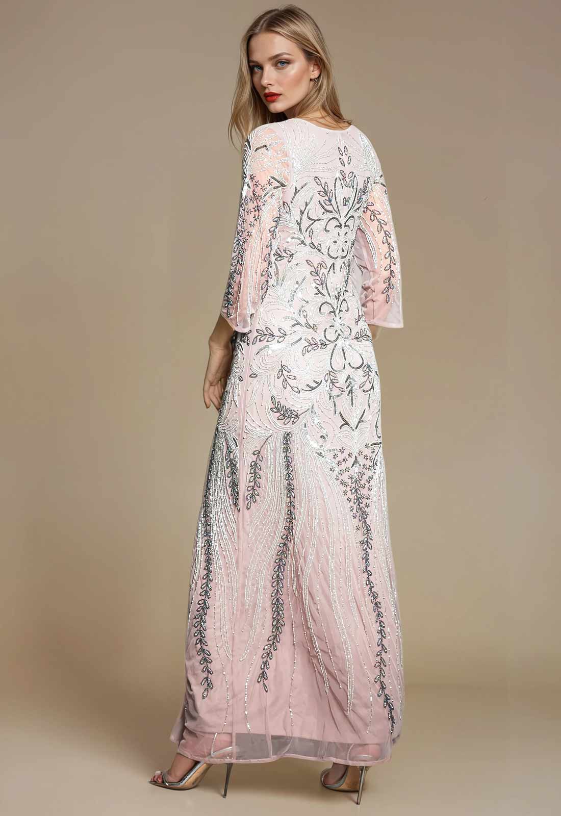 Woman wearing a long, elegant dress with floral patterns on a beige background