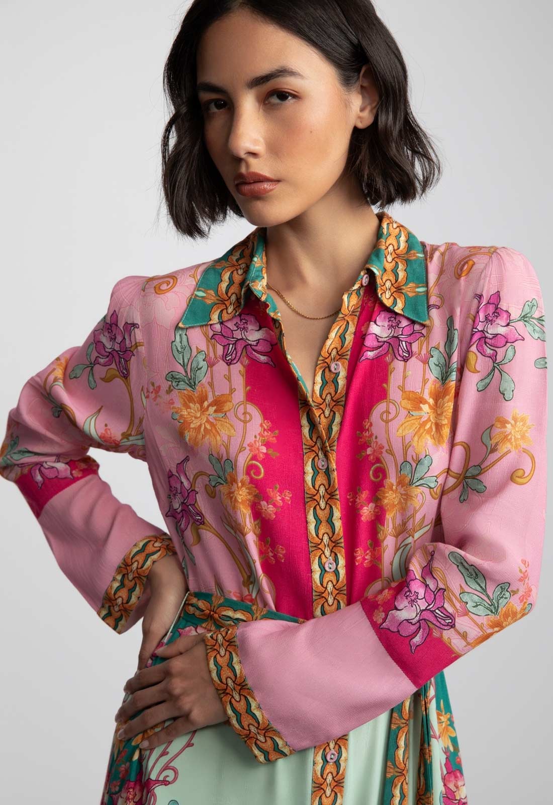 Woman wearing a colorful floral blouse with a pink background