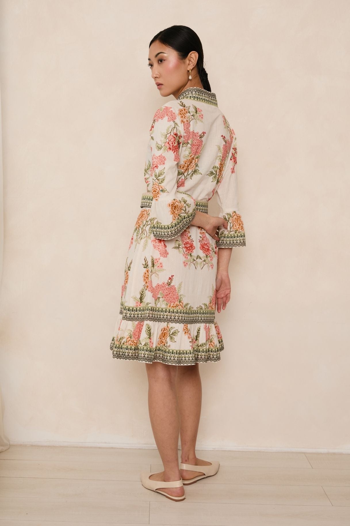 Woman wearing a floral dress with intricate patterns against a plain background