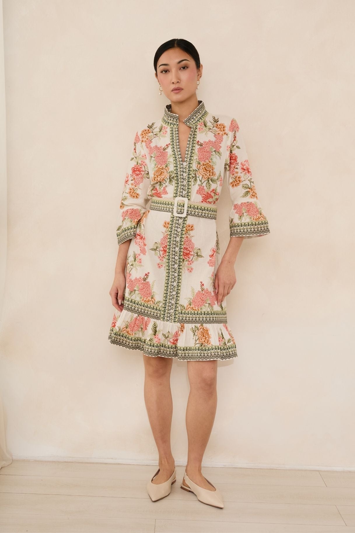 Woman wearing a floral dress with intricate patterns against a plain background