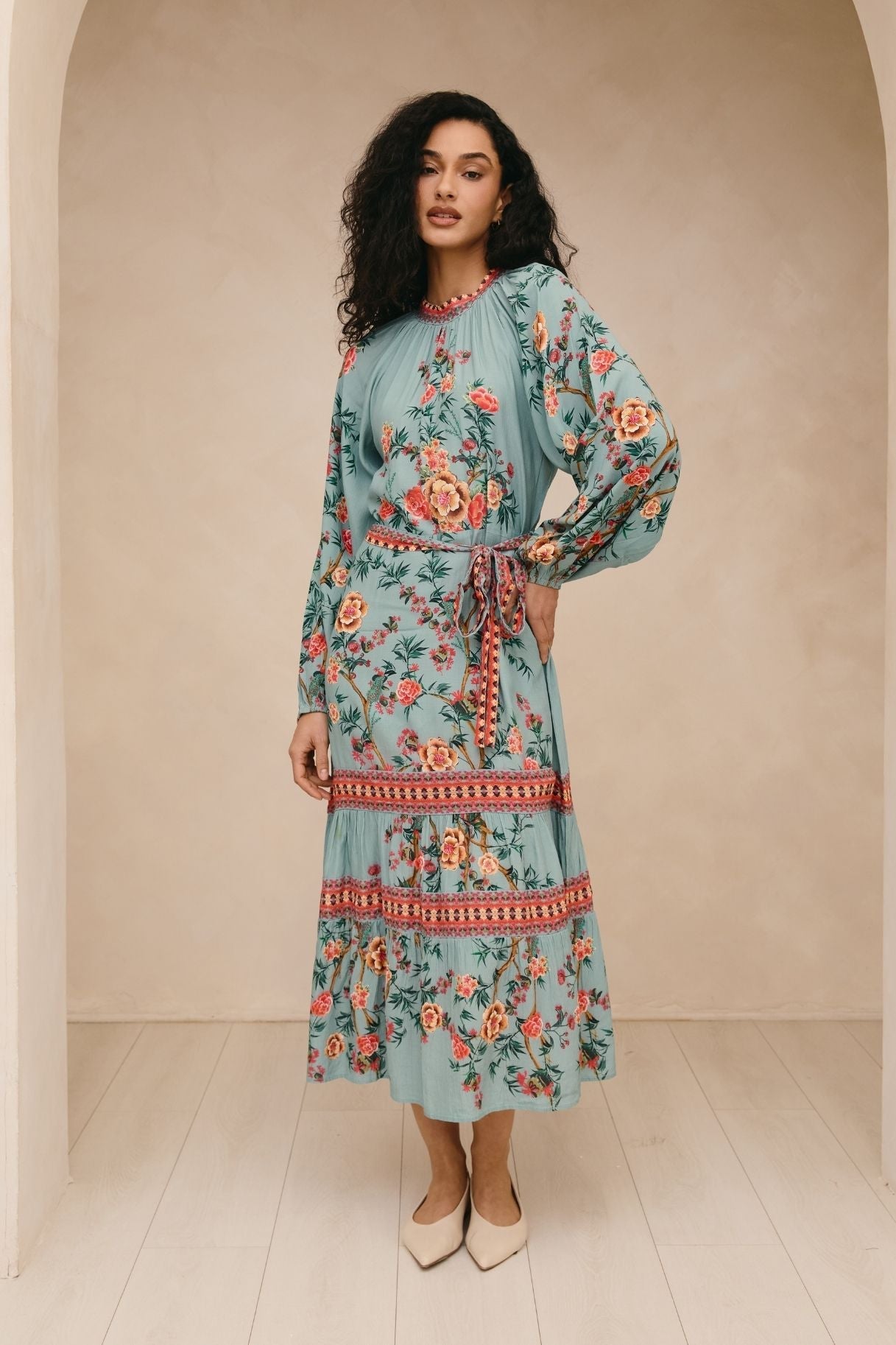Woman wearing a floral dress standing in a neutral setting
