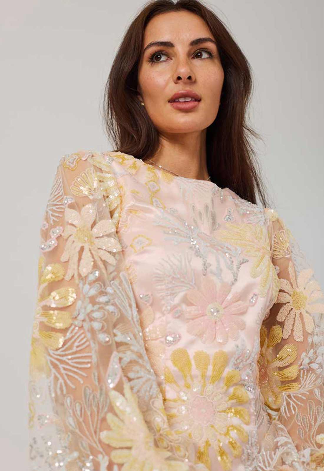 Woman wearing a floral embroidered dress with a plain background