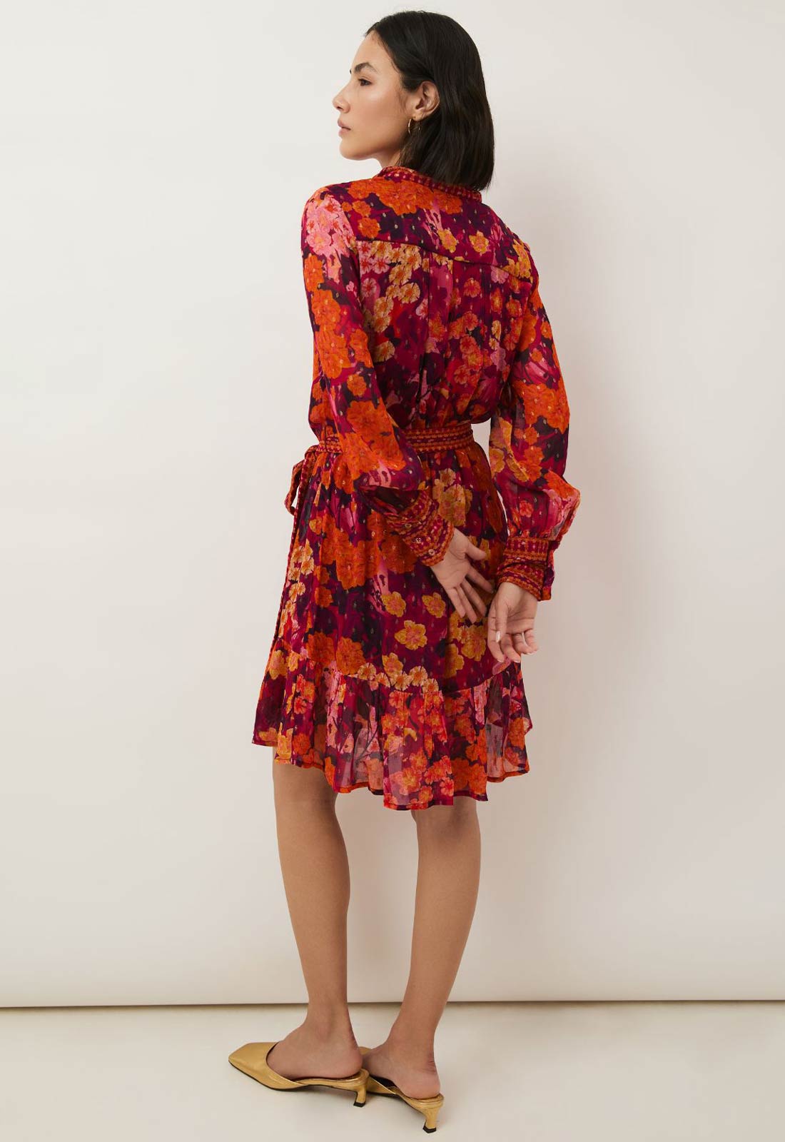 Woman wearing a colorful floral dress against a white background
