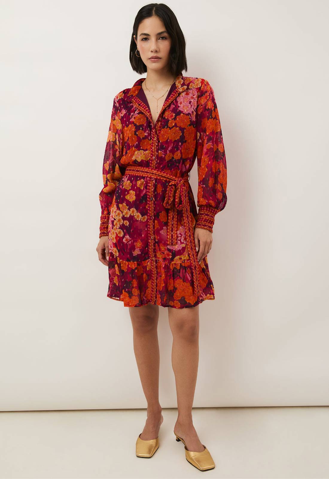 Woman wearing a colorful floral dress against a white background