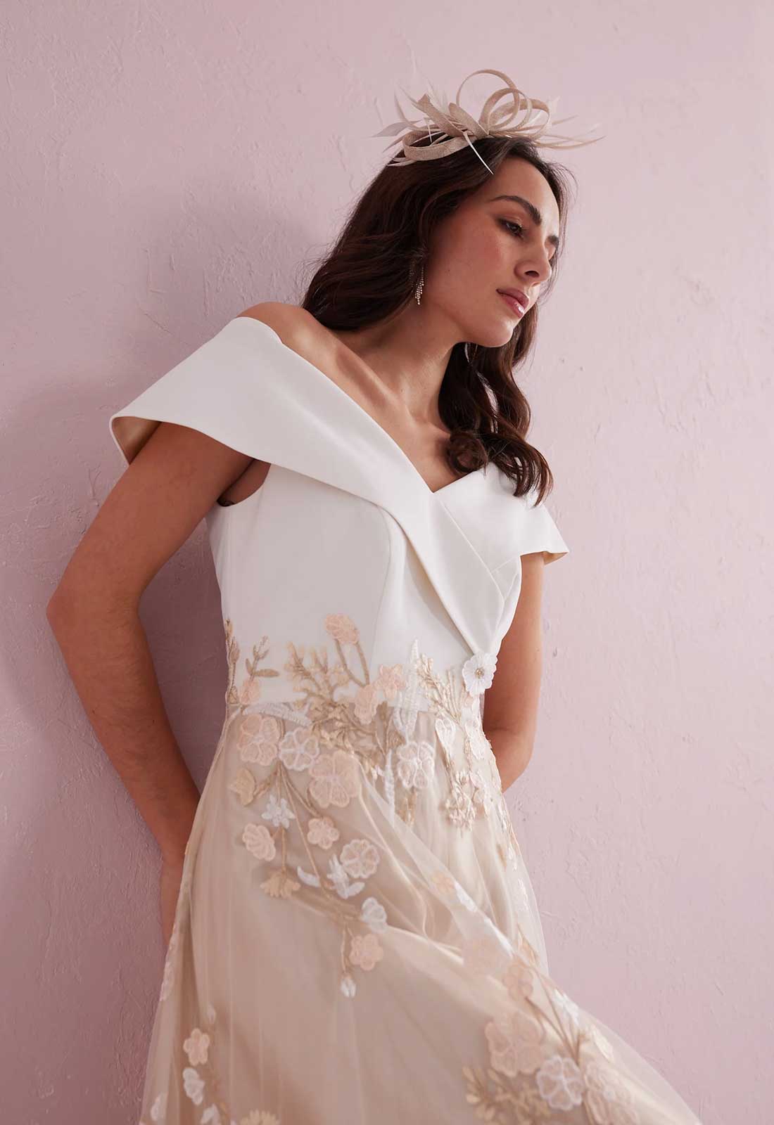 Woman wearing a white and beige floral dress against a pink background