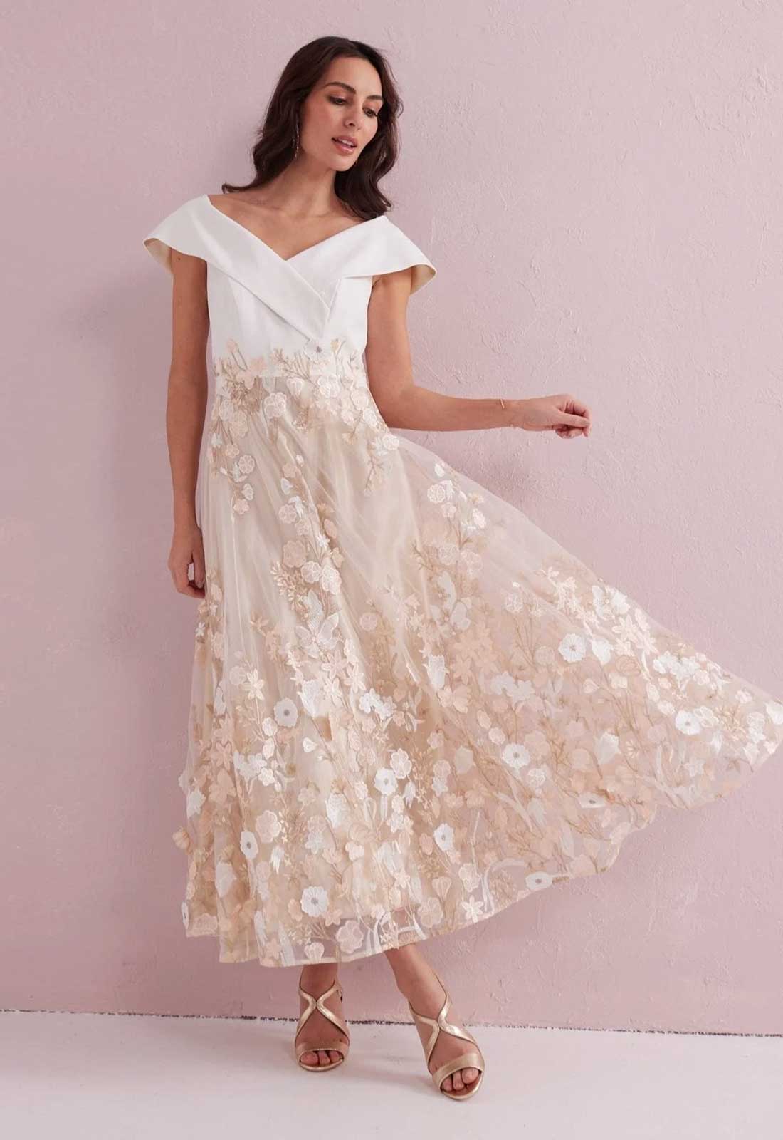 Woman wearing a white and beige floral dress against a pink background