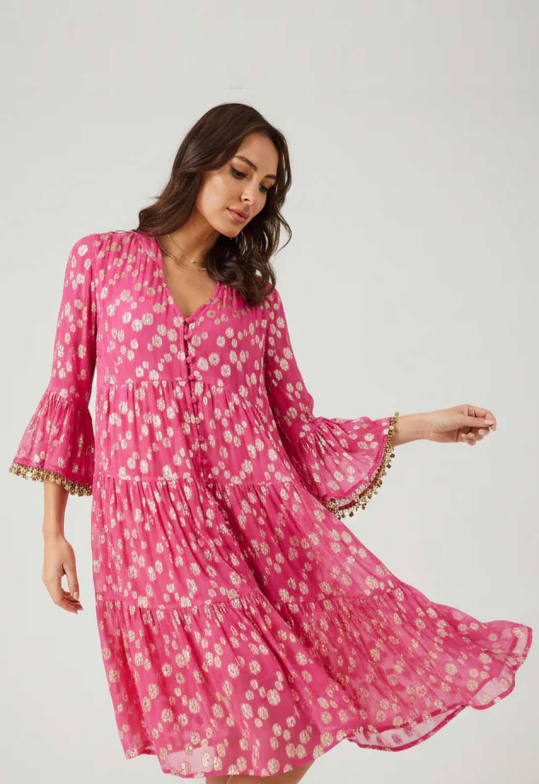 Woman wearing a pink floral dress with gold trim on a white background