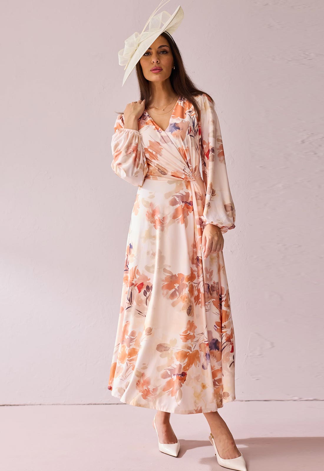 Woman wearing a floral dress and white hat against a plain background