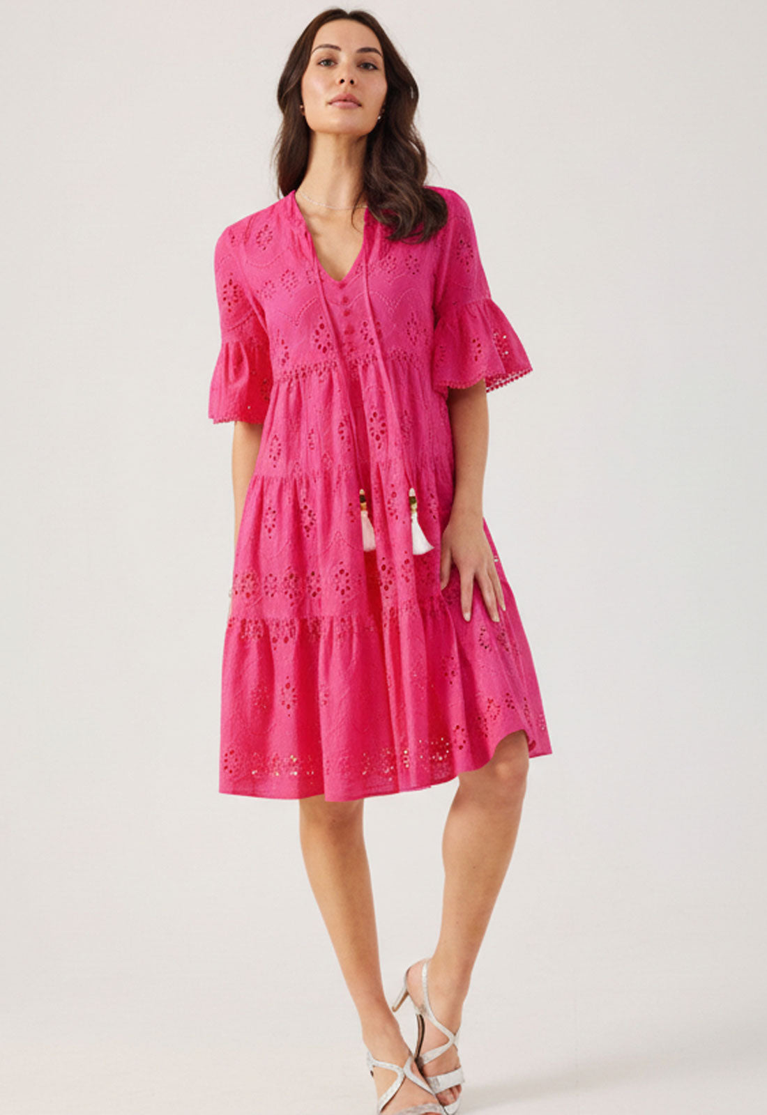 Woman wearing a pink dress with lace details on a white background