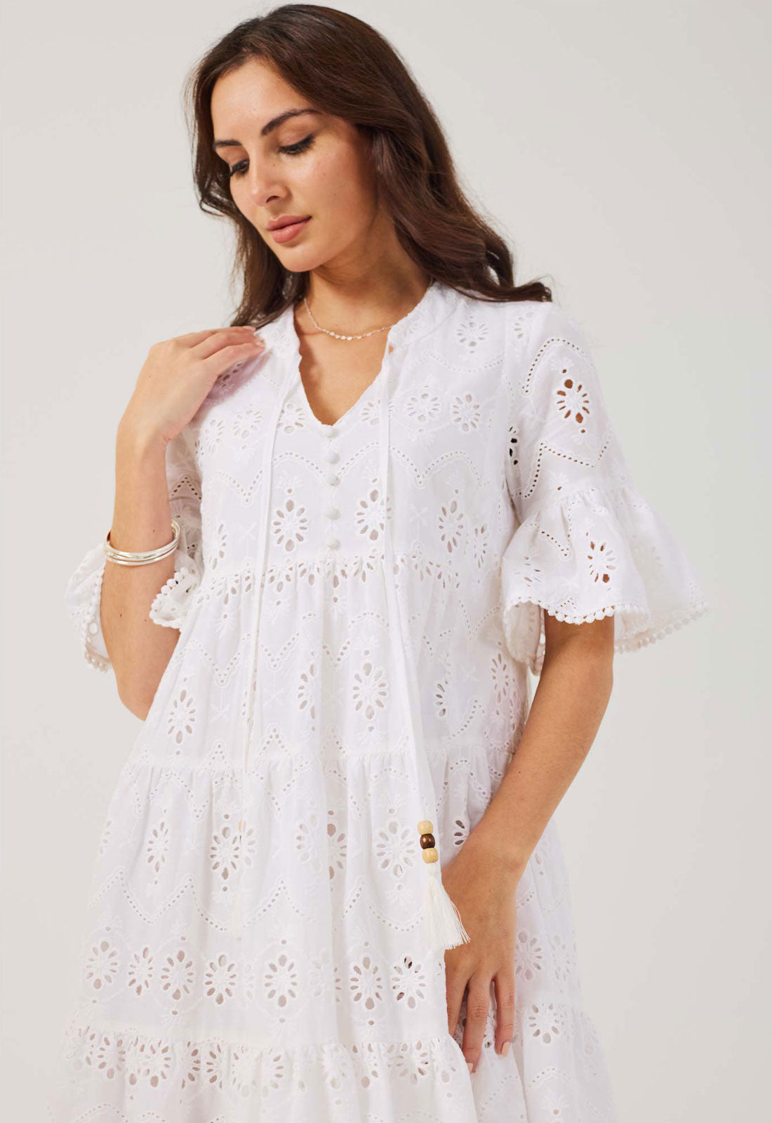 Woman wearing a white dress with floral patterns on a plain background