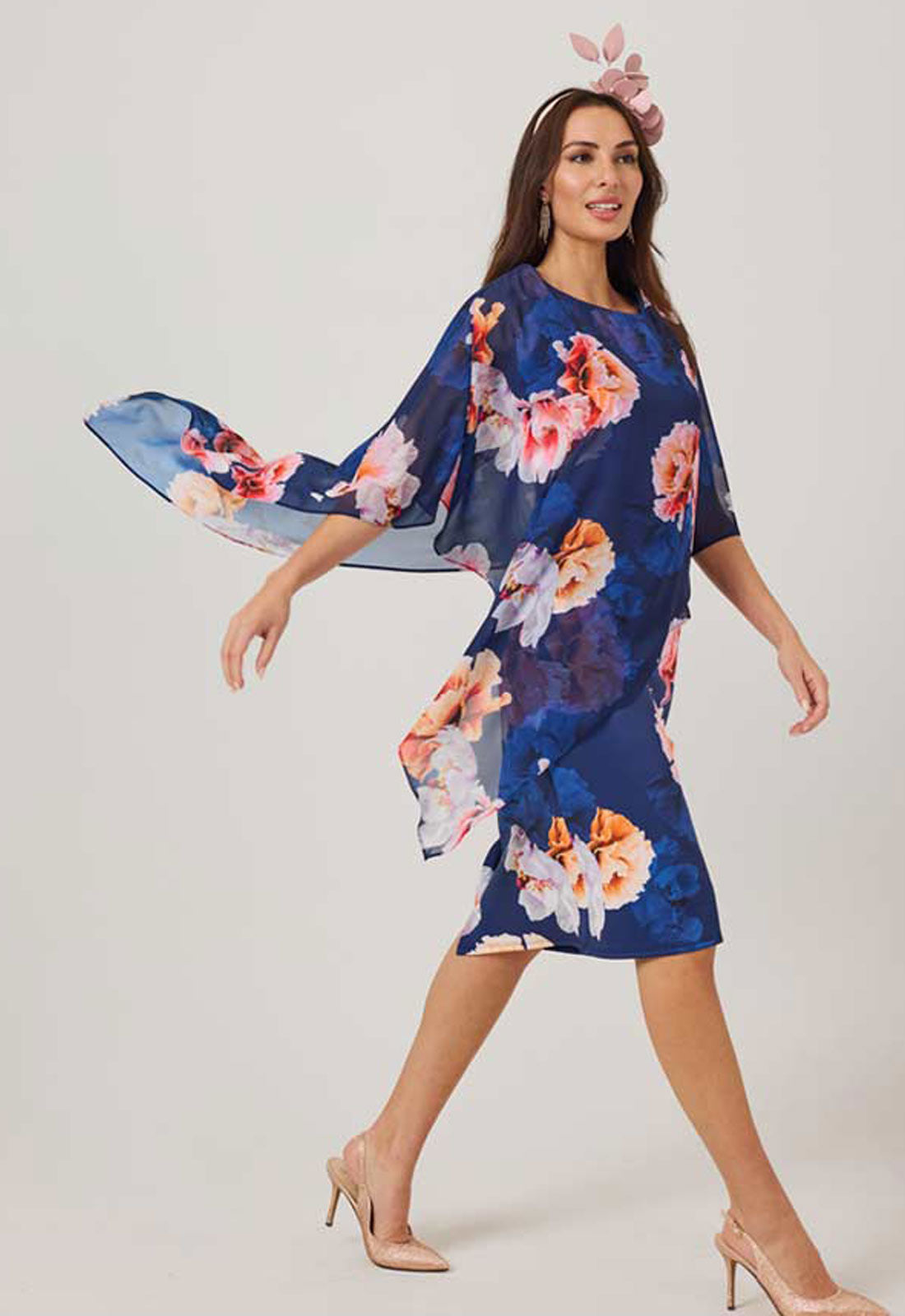 Woman wearing a blue floral dress with a plain background