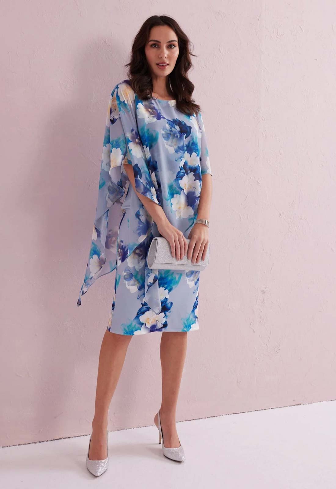 Woman wearing a blue floral dress against a light pink background