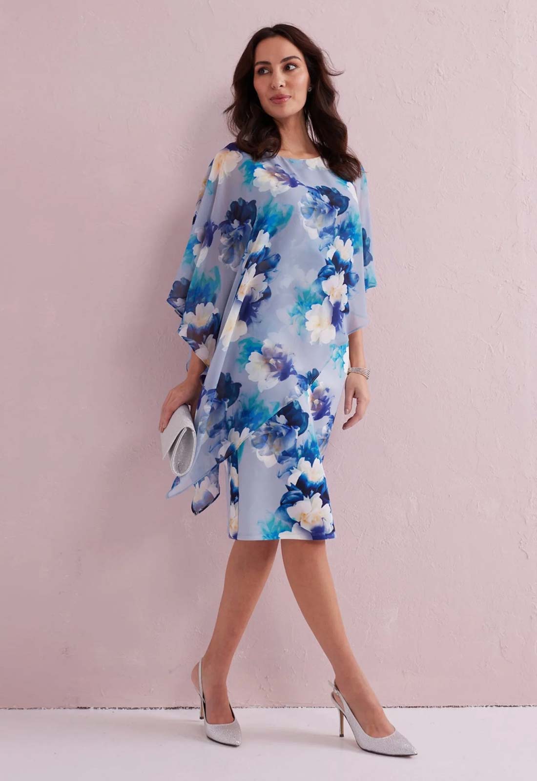 Woman wearing a blue floral dress against a pink background