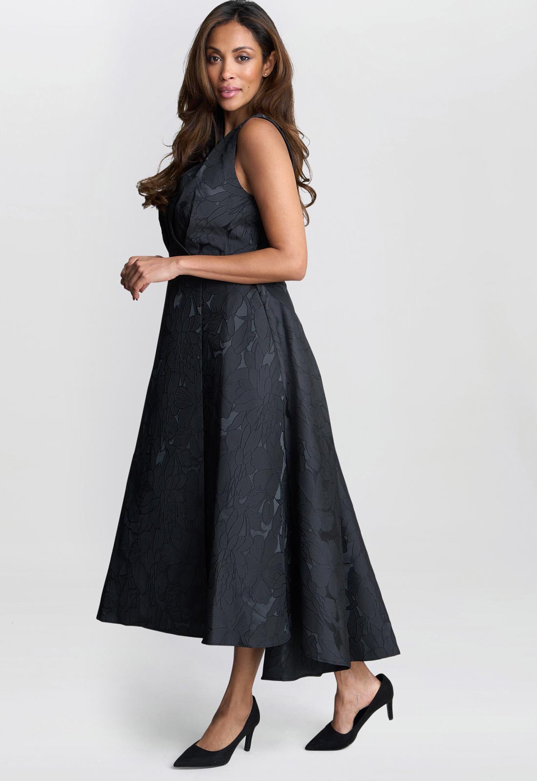 Woman wearing a black sleeveless dress with a pattern on a white background