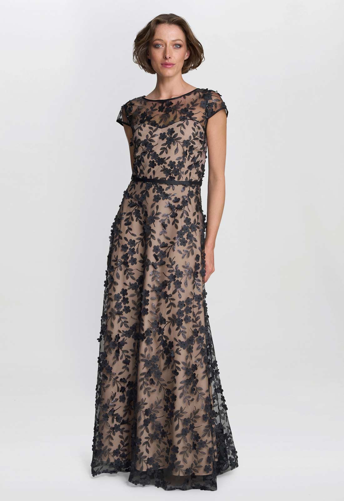Woman wearing a long, floral lace dress on a white background