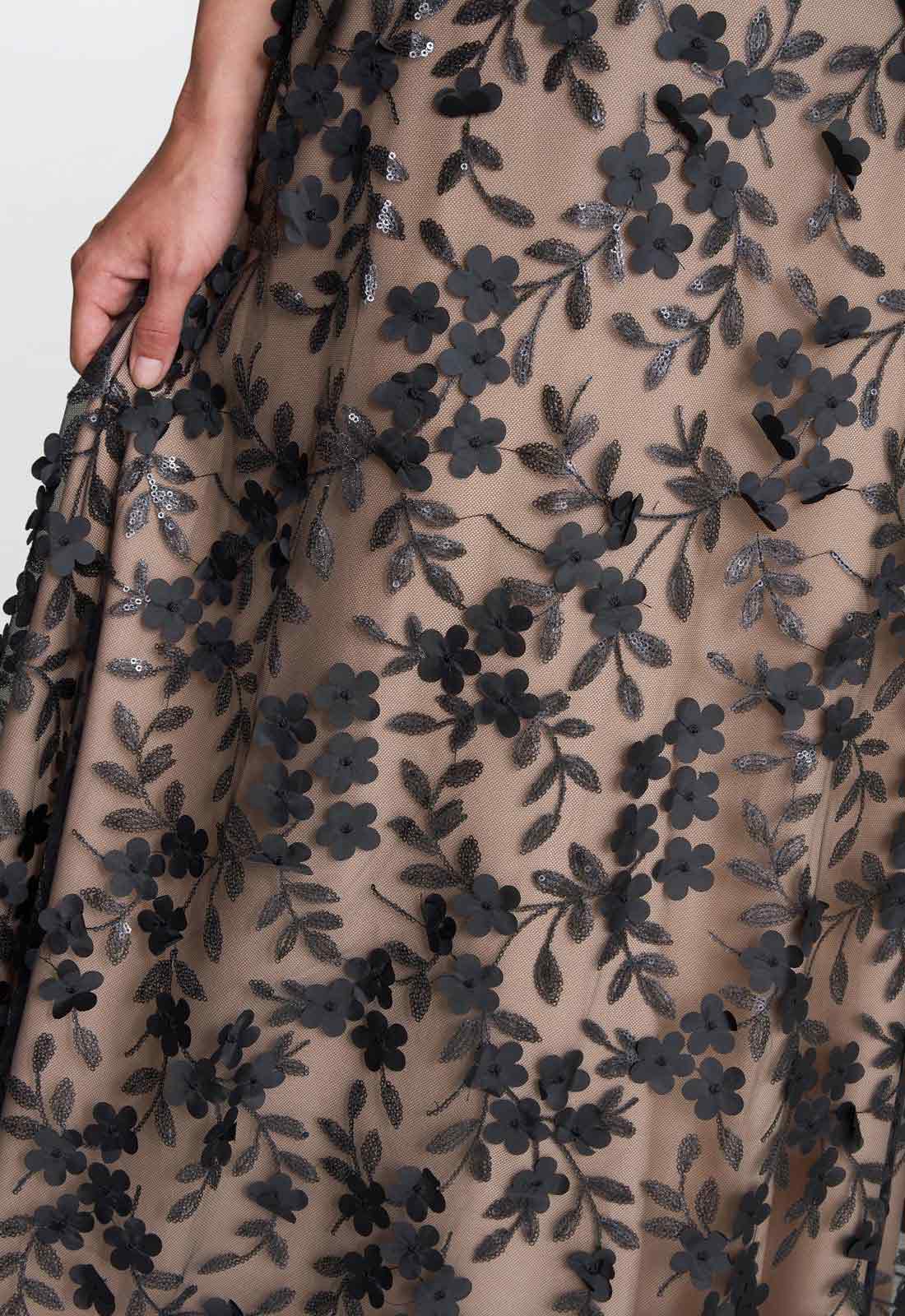 Close-up of a beige fabric with black floral embroidery on a white background