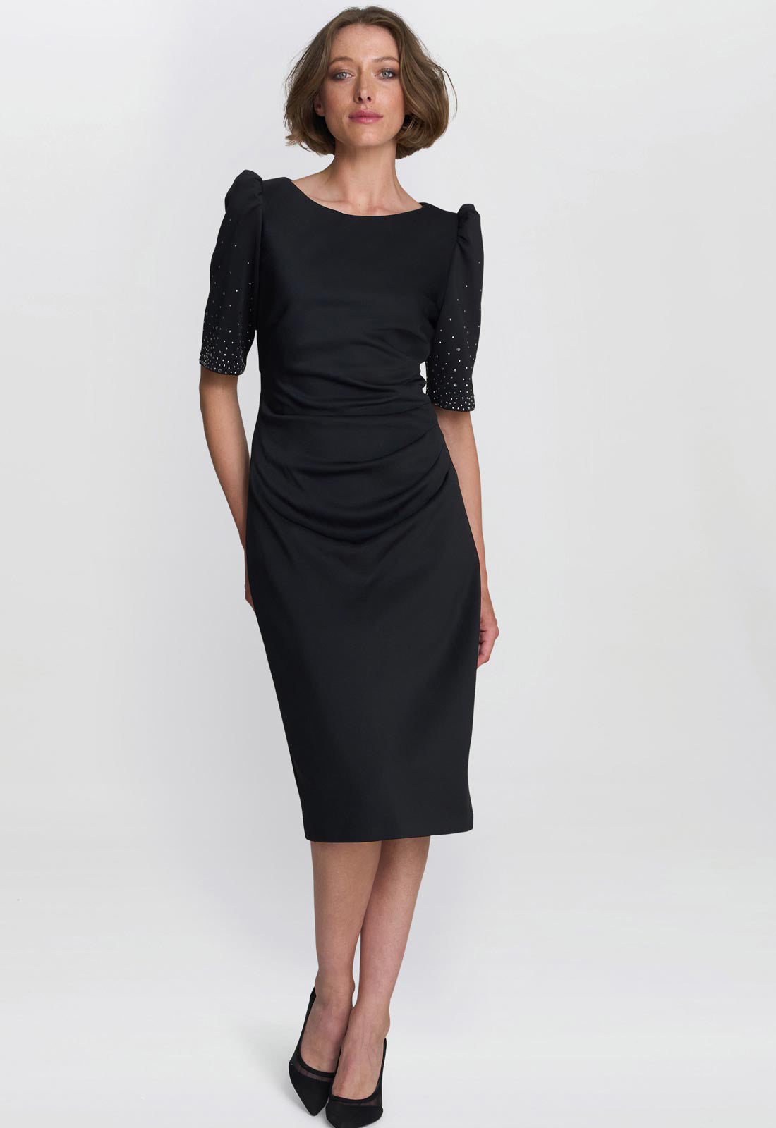 Woman wearing a black dress with embellished sleeves on a white background