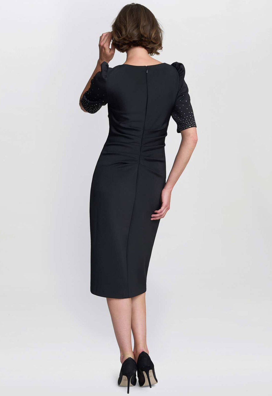 Woman wearing a black dress with short sleeves on a white background