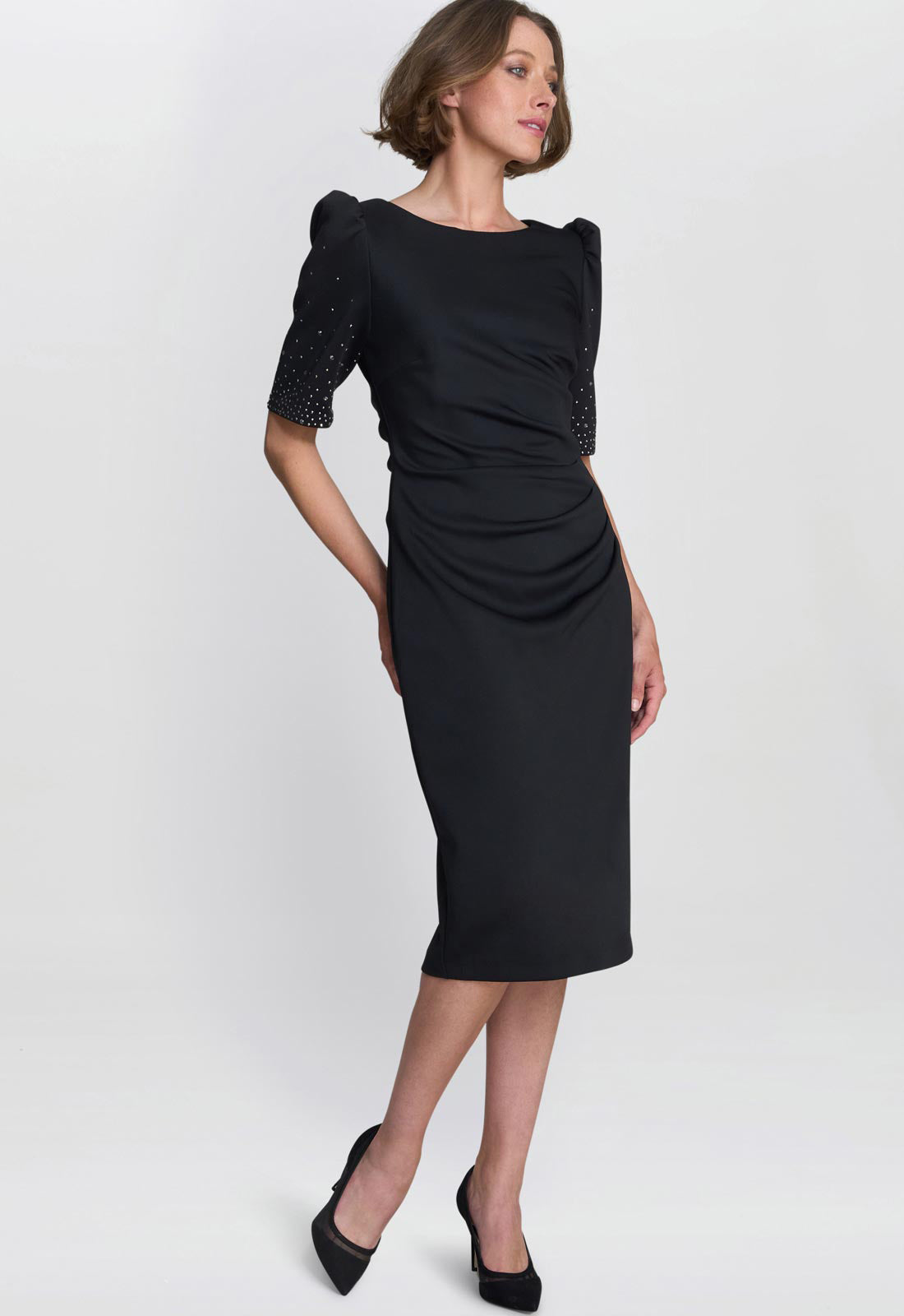 Woman wearing a black dress with embellished sleeves on a white background