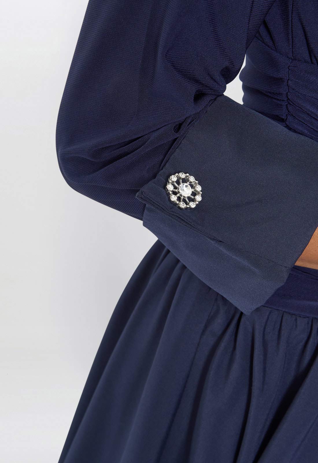 Navy blue dress with a decorative brooch on a white background