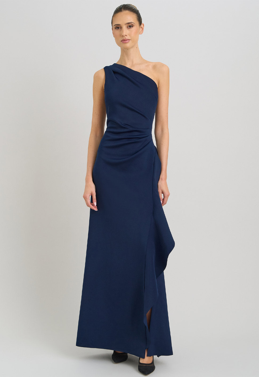 Woman wearing a navy one-shoulder dress on a light gray background