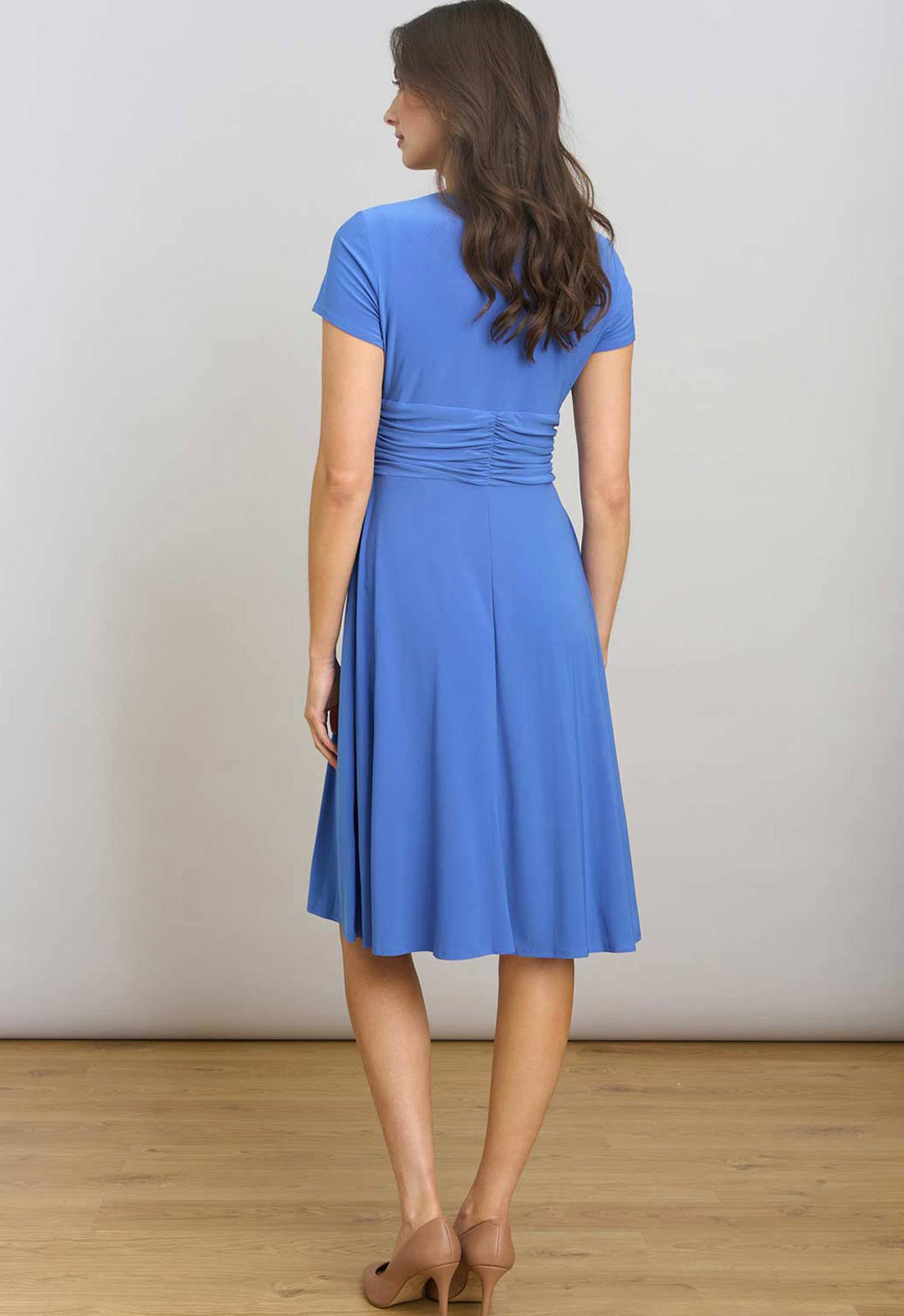 Woman wearing a blue dress standing against a plain background