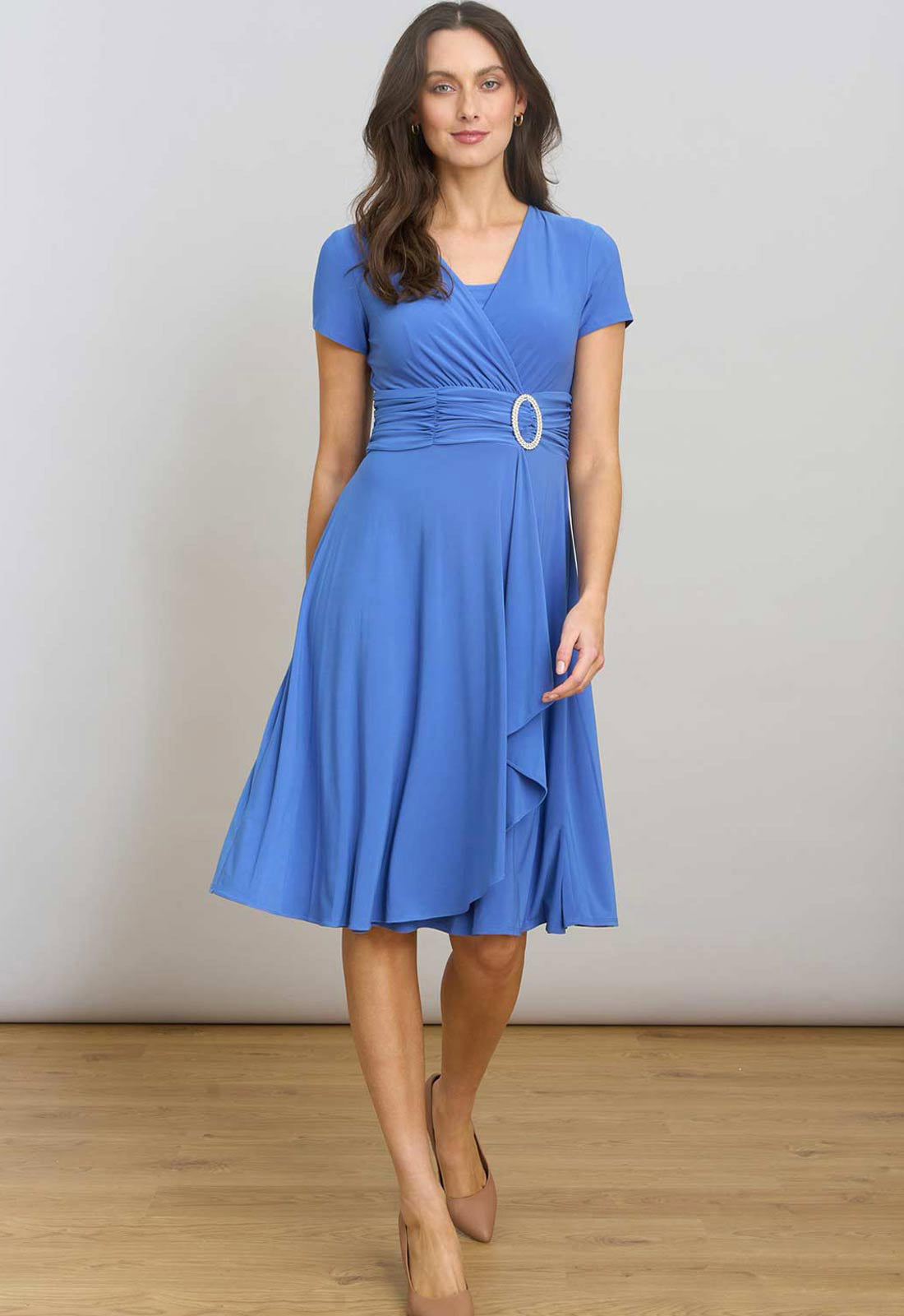 Woman wearing a blue dress with a belt against a plain background