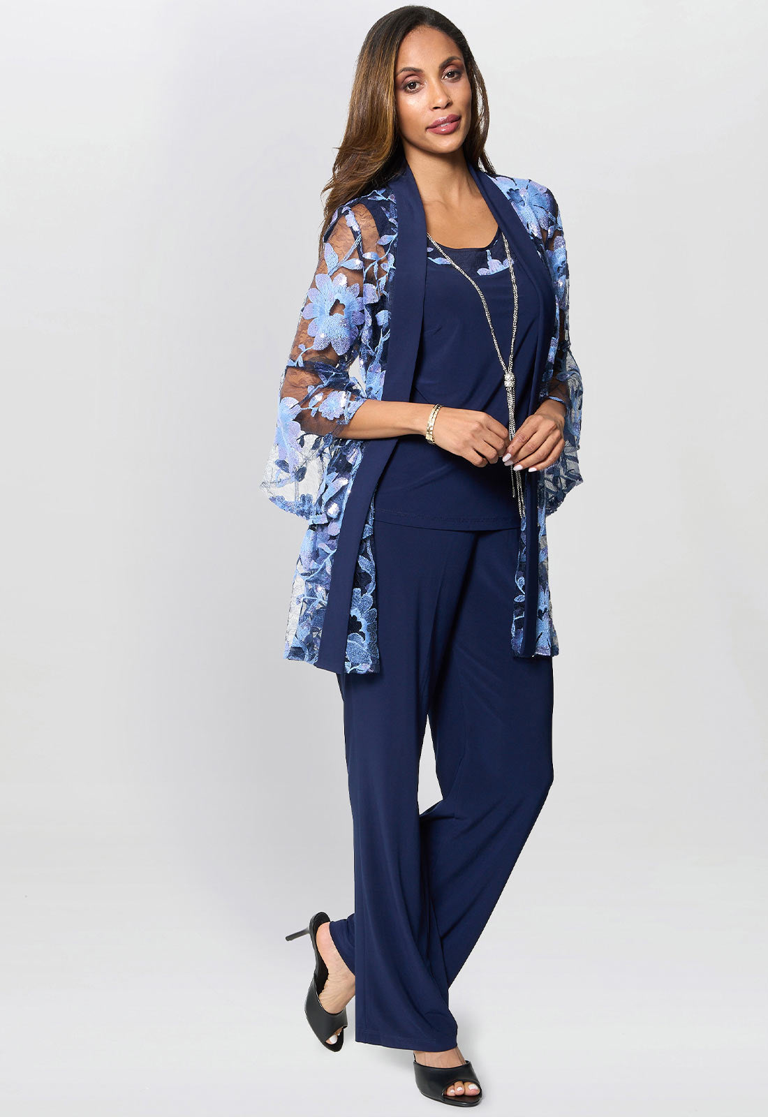 Woman wearing a navy outfit with a floral jacket on a white background