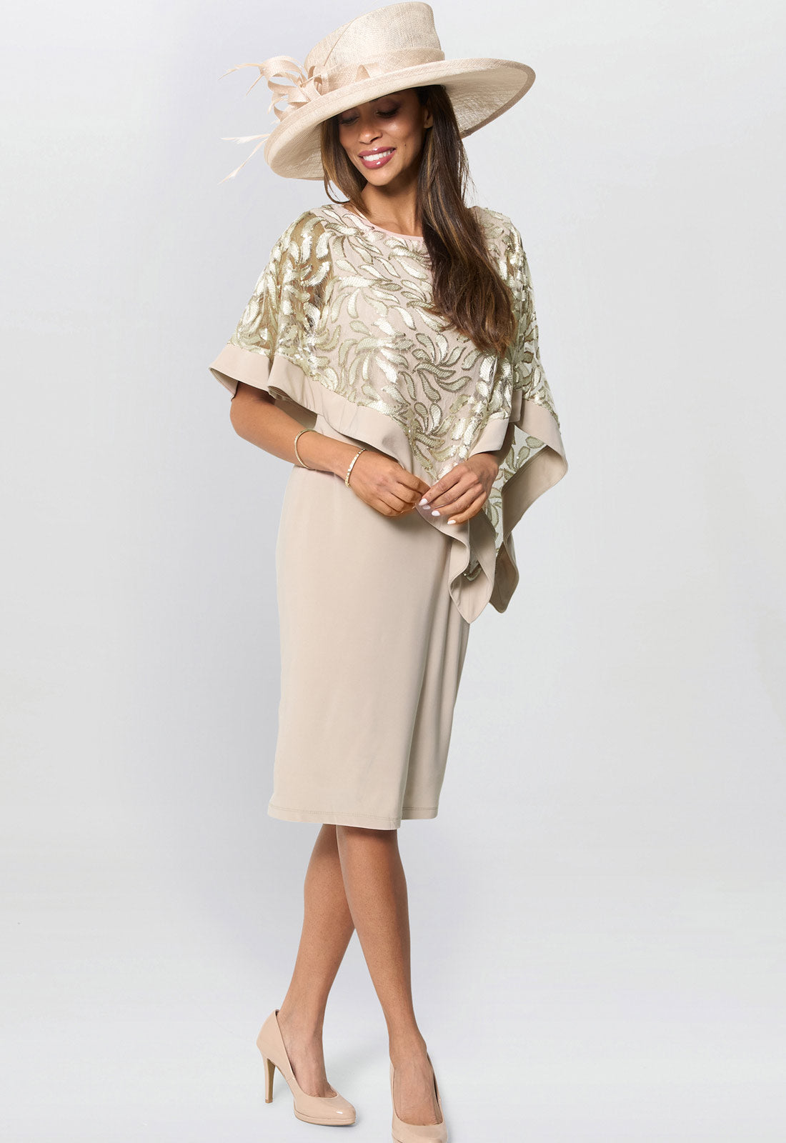Woman wearing a beige dress with a gold shawl and hat on a white background