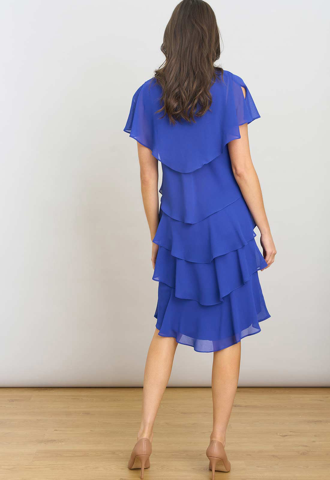 Woman wearing a blue dress with ruffled layers against a white background