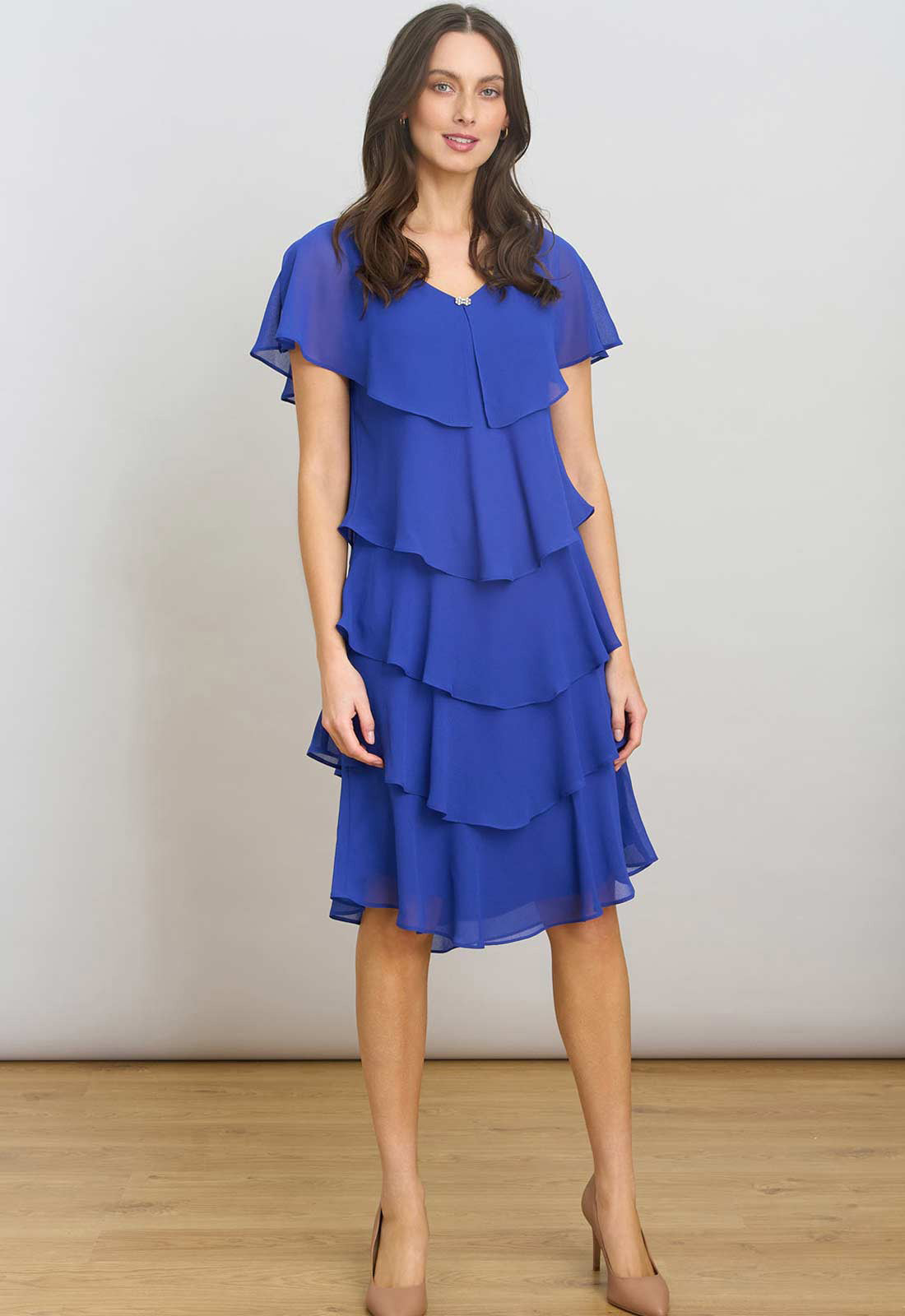 Woman wearing a blue tiered dress against a plain background