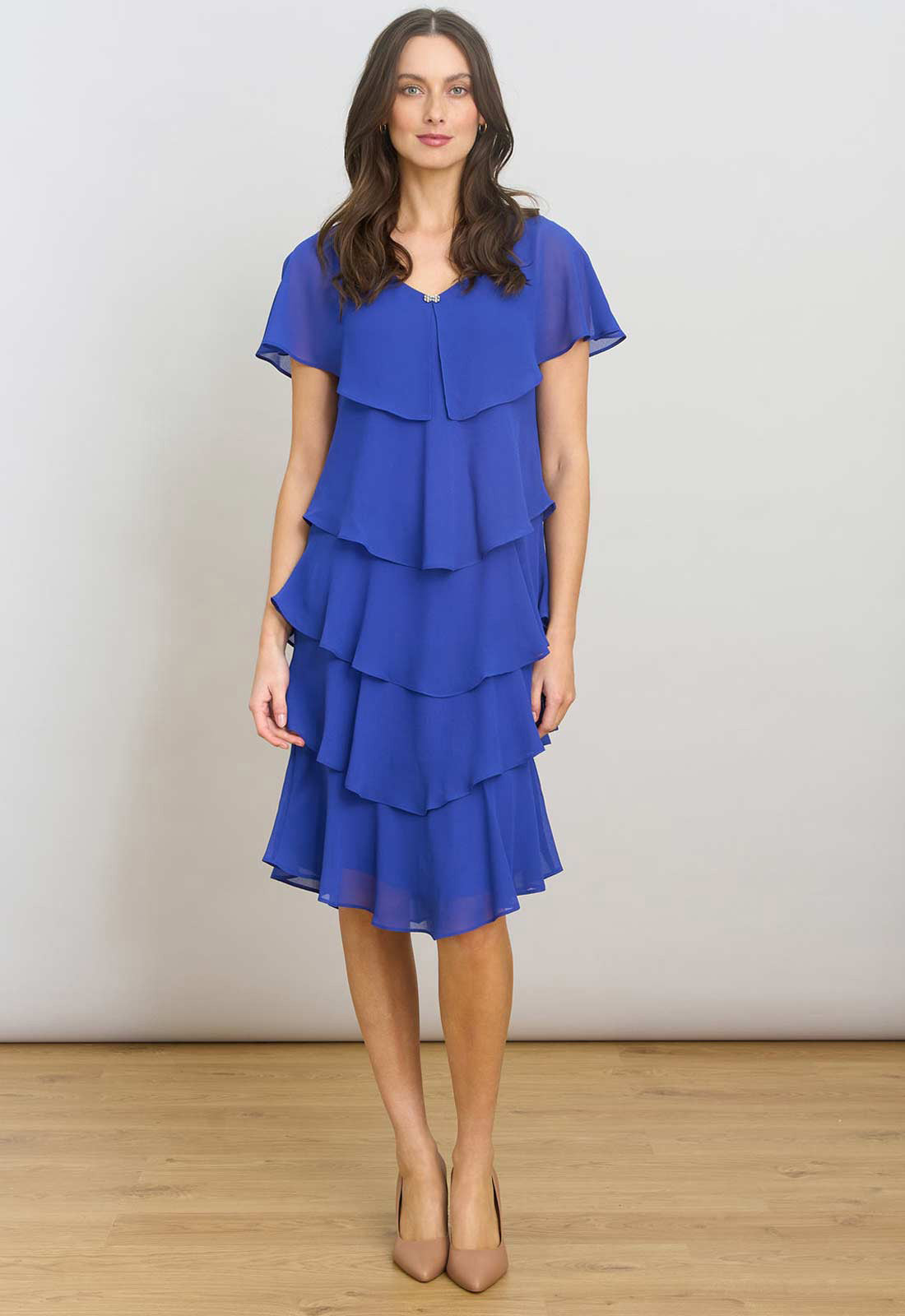 Woman wearing a blue dress with ruffled layers on a plain background