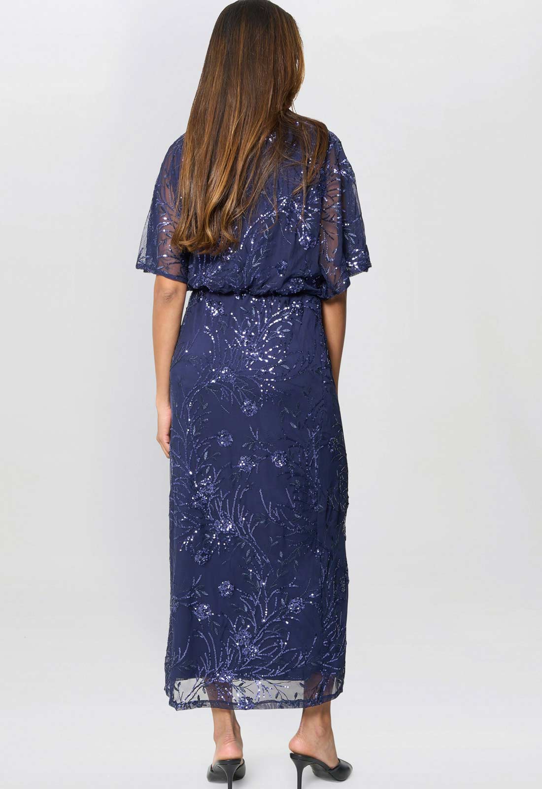 Woman wearing a navy blue floral dress against a white background