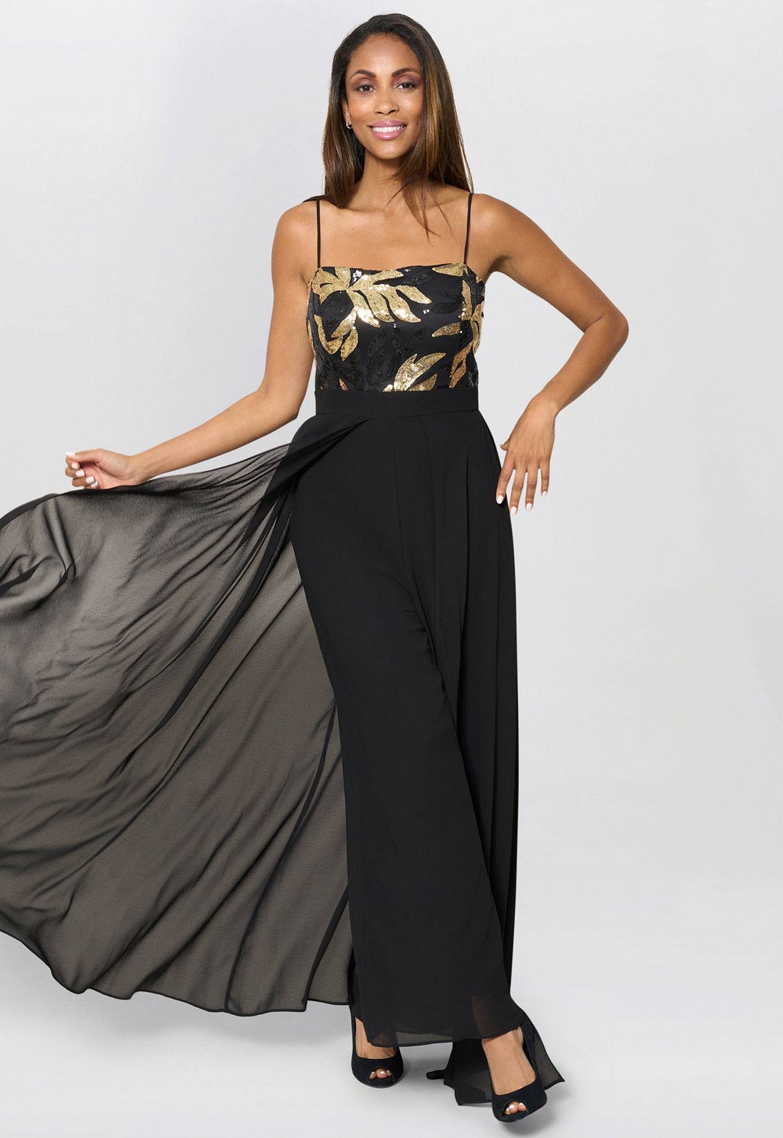 Woman wearing a black and gold dress with a flowing skirt on a white background
